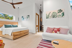 Een moderne slaapkamer met een houten bed, een witte bank en een groot raam.