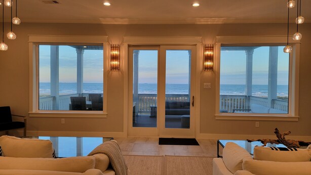 A spacious living room with large windows offering ocean views, a cozy seating area, and a modern design.