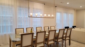 A dining area with a long table, chairs, and a chandelier.