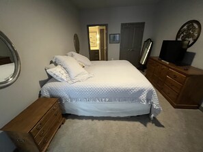 Ein Schlafzimmer mit einem Bett, einer Holzkommode und einem Fernseher auf der Kommode.