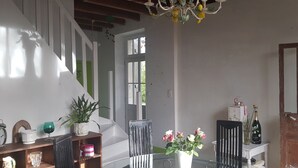 Um quarto com escada, mesa de jantar com cadeiras, um candelabro e uma janela.