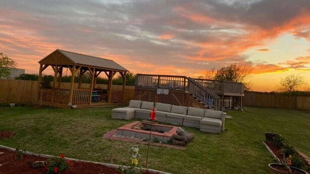 Un jardin avec un patio couvert, un foyer extérieur et une terrasse en bois.