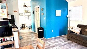 Un salon avec un mur d’accent bleu, une table à manger en bois et un canapé marron.