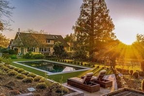Une maison avec une piscine, du mobilier d’extérieur et un jardin bien entretenu.