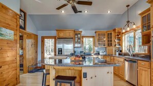 A spacious kitchen with wooden cabinets, a large island, stainless steel appliances, and a ceiling fan.