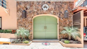 A building entrance with a green door, stone facade, and two lanterns. - San Miguel PV Rentals (Puerto Vallarta)