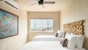 A bedroom with a large window, a ceiling fan, and a decorative headboard. - San Miguel PV Rentals (Puerto Vallarta)