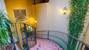 A spiral staircase with a metal railing, a wall-mounted light fixture, and a potted plant. - San Miguel PV Rentals (Puerto Vallarta)