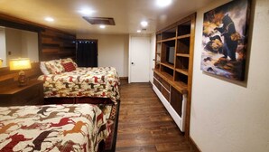 Quarto com duas camas, um guarda-roupa de madeira, um quadro e um abajur.