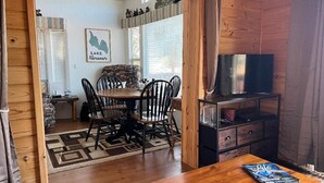 Una habitación acogedora con una mesa de comedor de madera, sillas y un televisor sobre un mueble de madera.