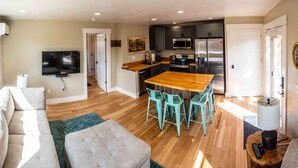 A modern living room with a sofa, a coffee table, and a TV mounted on the wall. - Charming Downtown Cody Cottage (#1) (Cody)
