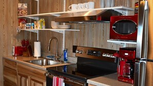 A modern kitchen with wooden cabinetry, stainless steel appliances, and a built-in oven. - Charming Cabin Retreat in Texas Hill Country (Boerne)