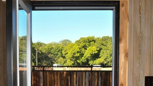 A wooden door with a view of a fenced outdoor area and a clear blue sky. - Charming Cabin Retreat in Texas Hill Country (Boerne)