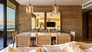 A modern dining area with a round table, wicker chairs, and hanging pendant lights. - Private Hot Tub • Ocean View • GYM • Free Parking (San José del Cabo)