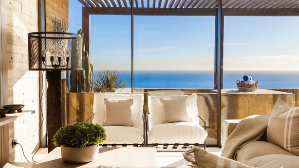 A balcony with a view of the sea, featuring a seating area with cushions and a potted plant. - Private Hot Tub • Ocean View • GYM • Free Parking (San José del Cabo)