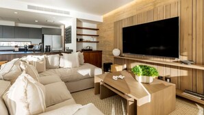 A modern living room with a large L-shaped sofa, a wooden coffee table with a plant, and a flat-screen TV mounted on the wall. - Private Hot Tub • Ocean View • GYM • Free Parking (San José del Cabo)