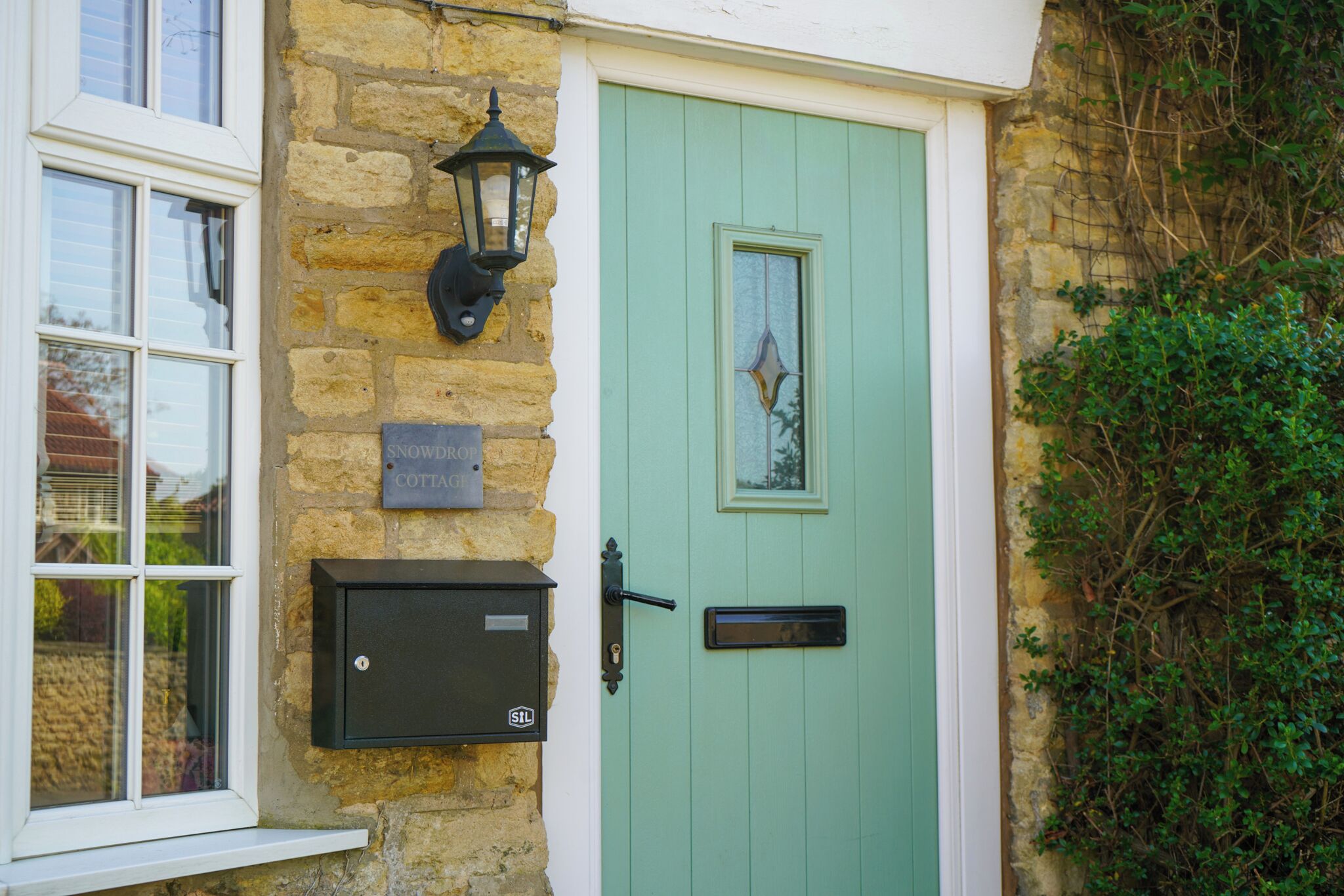 A stone building with a green door, a mailbox, and a window.