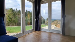 Una habitación con amplios ventanales que dan a un paisaje verde y árboles.