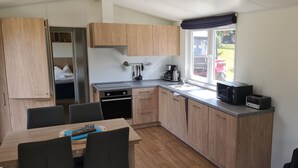 Una cocina compacta con muebles de madera, una mesa de comedor y un horno empotrado.