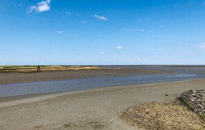 Ein weiter Strand, bewölkter Himmel, einige Personen in der Ferne und eine Kamera auf einem Stativ.