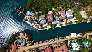 An aerial view of a coastal property with multiple buildings, a dock, and a swimming pool. - Casa de Amigos, Island Townhome (Placencia)
