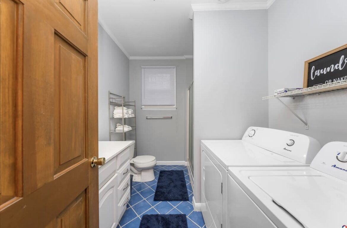 Een kleine badkamer met toilet, wastafel en een wasmachine.