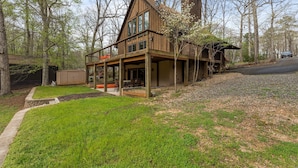 A two-story wooden cabin with large windows, a covered porch, and a chimney.