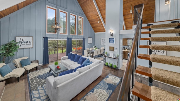 A spacious living area with a high ceiling, a large sofa, a coffee table, and a staircase with a cat tree.