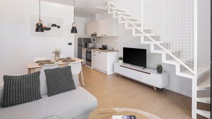 A modern living space with a staircase, kitchen, dining area, and a flat-screen TV. - NEK Suites - Adults Only (Chania)