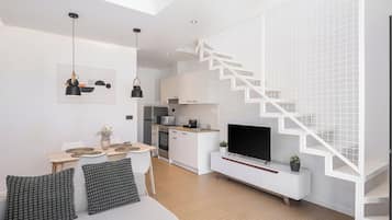 Um espaço de estar moderno com escada, cozinha, área de jantar e televisão de tela plana.