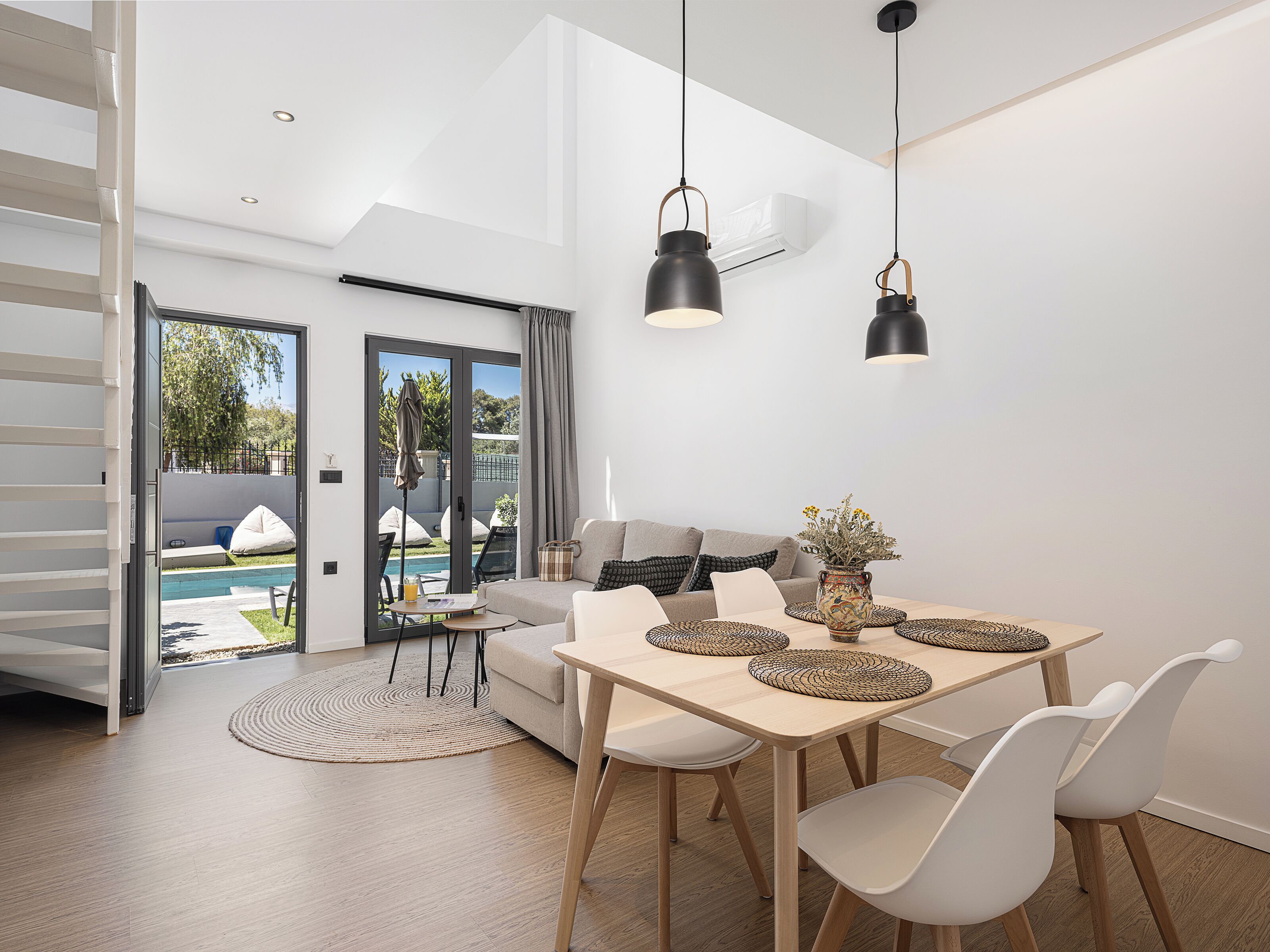 Um espaço moderno com área de jantar, sofá e vista para uma piscina ao ar livre.