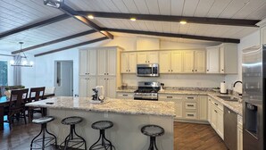 Una cocina amplia con una isla grande, taburetes de bar y electrodomésticos modernos.