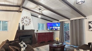 Una sala de estar con chimenea, sofás marrón oscuro, una mesa de centro y un televisor montado en la pared.
