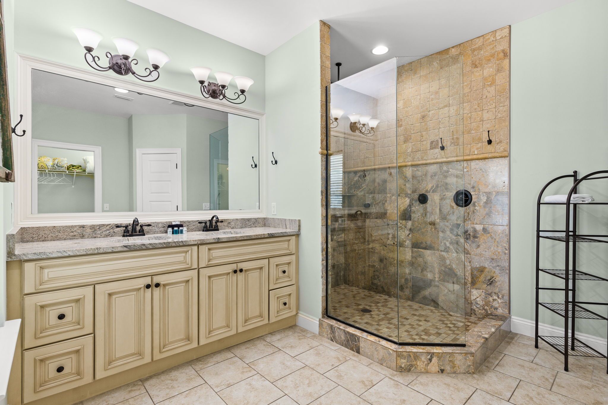 A bathroom with a double vanity, a glass-enclosed shower, and a towel rack.