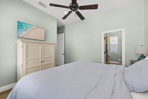 Une chambre à coucher avec un lit, un ventilateur de plafond, une armoire et un tableau accroché au mur.