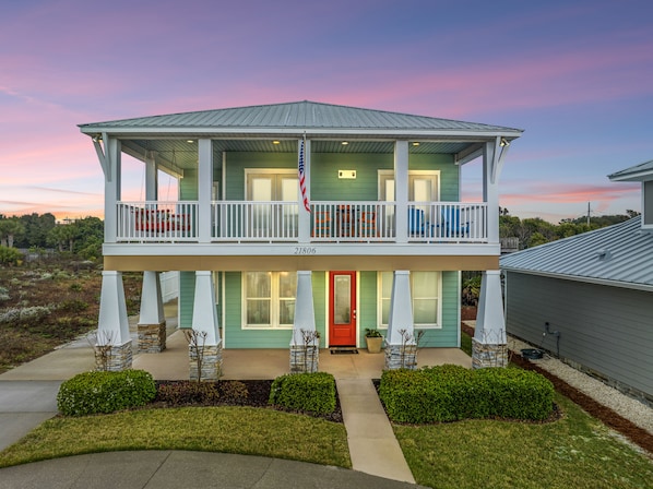 A two-story house with a balcony, a red door, and an American flag. - 5 Bed, 5 Bath Beach Home/only a 3 Minute Walk To The Beach! Sleeps 12 (Panama City Beach)