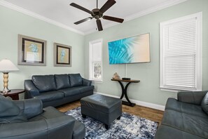 A living room with a dark leather sofa, a coffee table, and a ceiling fan. - 5 Bed, 5 Bath Beach Home/only a 3 Minute Walk To The Beach! Sleeps 12 (Panama City Beach)