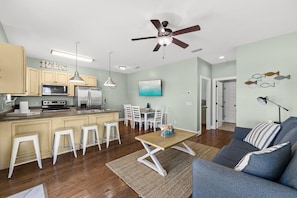 A modern kitchen with a dining area, a ceiling fan, and a living room with a sofa and a coffee table. - 5 Bed, 5 Bath Beach Home/only a 3 Minute Walk To The Beach! Sleeps 12 (Panama City Beach)