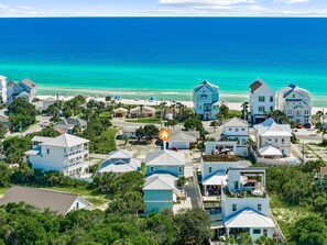 Un quartier résidentiel situé sur la côte, avec des propriétés donnant sur la plage, une vue dégagée sur l’océan et un mélange de maisons à un ou plusieurs étages.