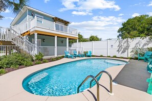 A swimming pool with a wooden deck and lounge chairs, surrounded by a white fence and greenery. - 5 Bed, 5 Bath Beach Home/only a 3 Minute Walk To The Beach! Sleeps 12 (Panama City Beach)