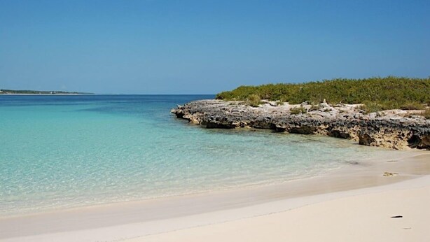 A beach with clear turquoise water, white sand, and rocky outcrops. - One Palm Hill 3 Bedroom Villa (Governor's Harbour)