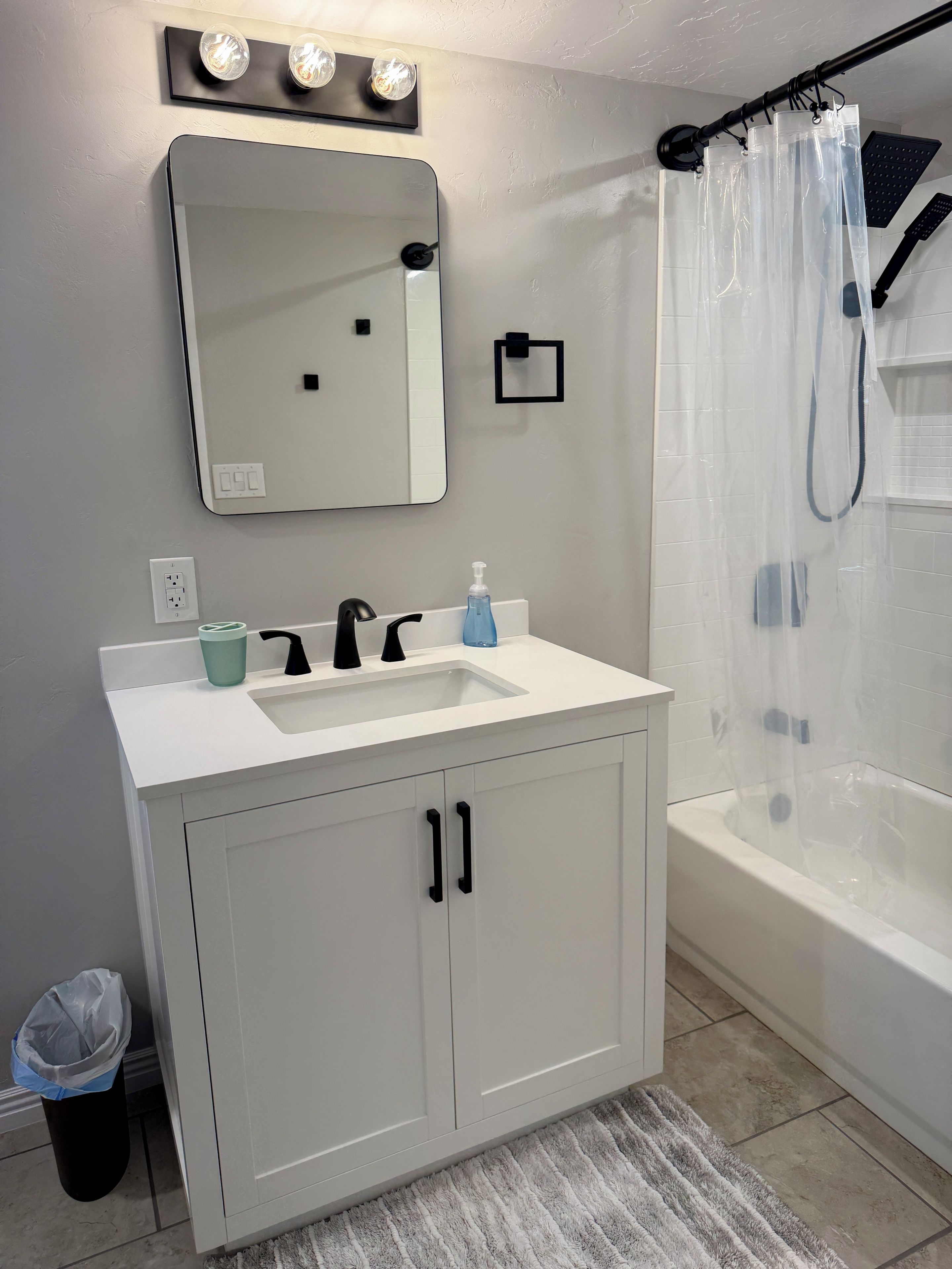 A bathroom with a white sink, a mirror, a shower curtain, and a bathtub.
