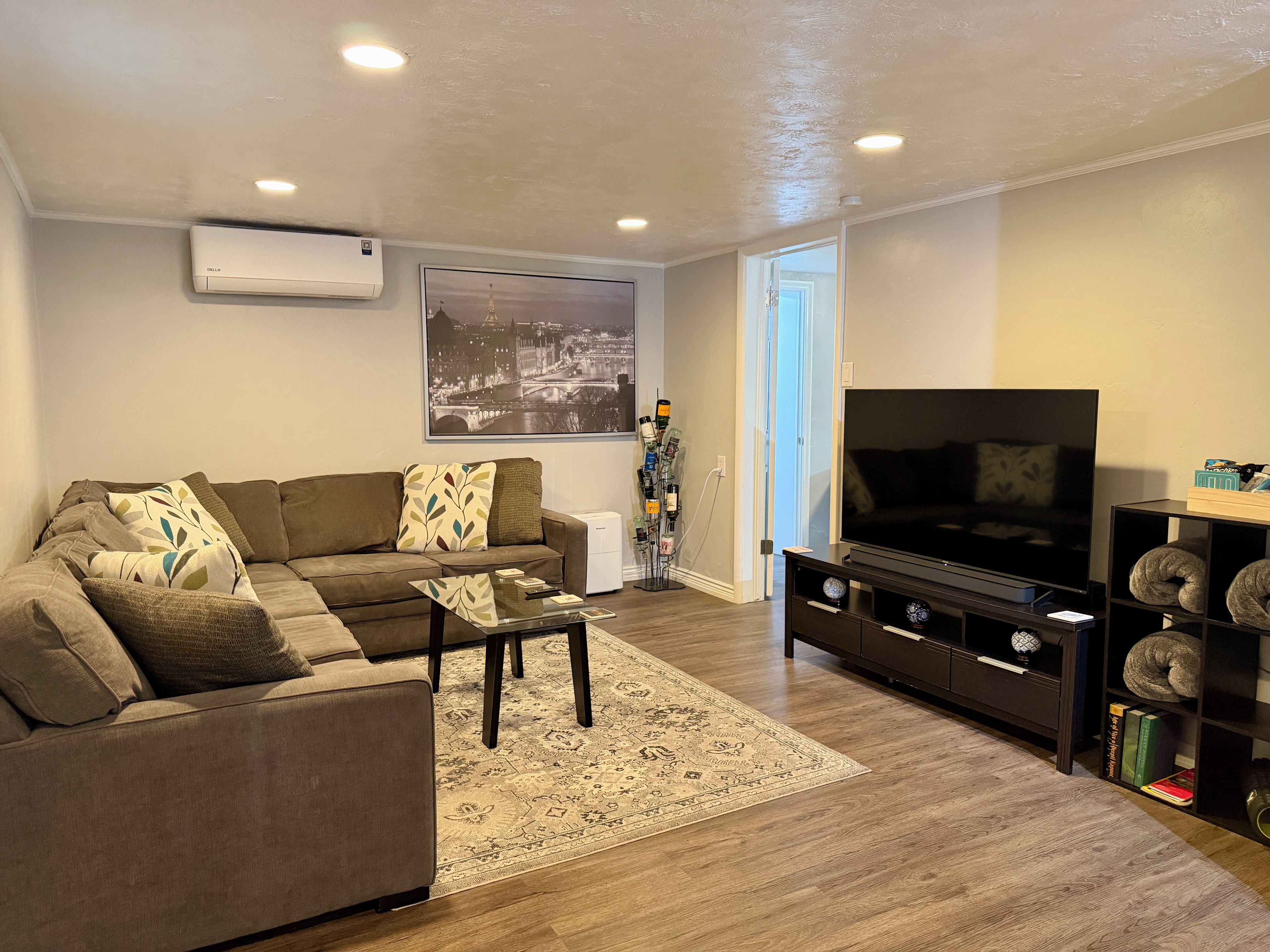 A living room with a sofa, coffee table, TV stand, and a bookshelf.