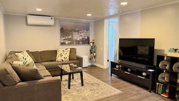 A living room with a sofa, coffee table, TV stand, and a bookshelf.