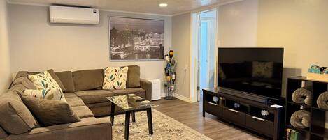 A living room with a sofa, coffee table, TV stand, and a bookshelf.