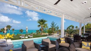 Un espace extérieur abrité comprenant une piscine, des chaises longues et une vue sur l’océan.