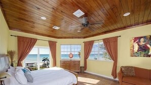 A bedroom with a large bed, wooden ceiling, and a view of the ocean. - Sand Dollar At Ten Bay Beach 4 Bedroom Home (South Palmetto Point)