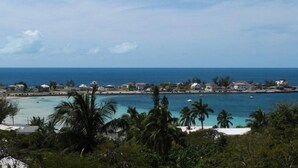 A coastal view with a beach, palm trees, and a clear sky. - Sand Dollar At Ten Bay Beach 4 Bedroom Home (South Palmetto Point)