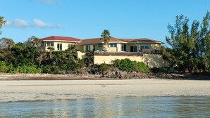 A coastal property with two houses, a sandy beach, and dense vegetation. - Sand Dollar At Ten Bay Beach 4 Bedroom Home (South Palmetto Point)