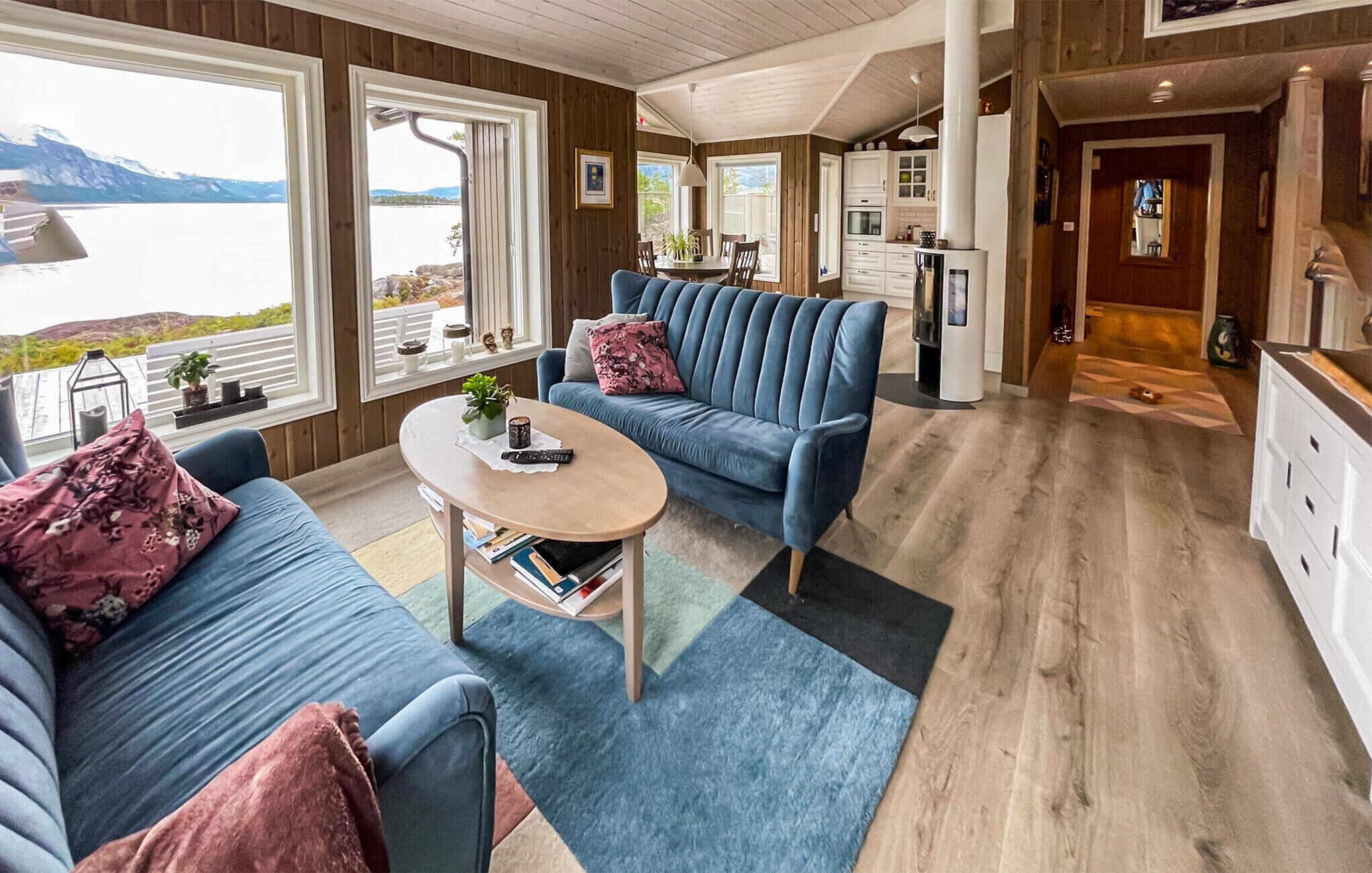 A cozy living room with a blue sofa set, a coffee table, and a view of a lake.